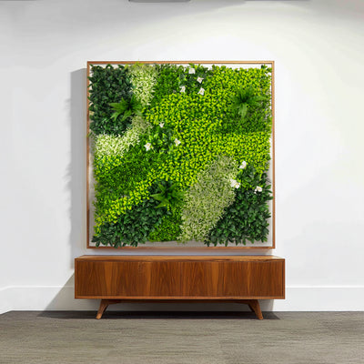 Artificial green wall art in a wooden frame above a mid-century modern console.