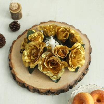 Gold rose flower arrangement with a candle on a rustic wooden slice.