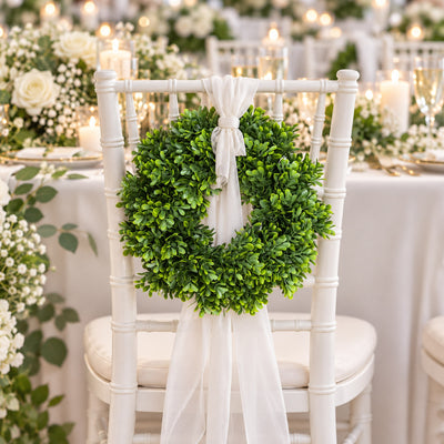 White wedding chair with greenery wreath and chiffon ribbon at elegant reception