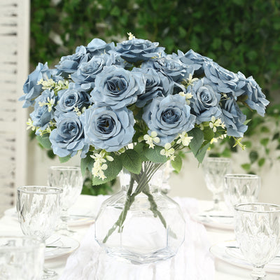 Blue rose bouquet in a clear vase on a decorative table setting.