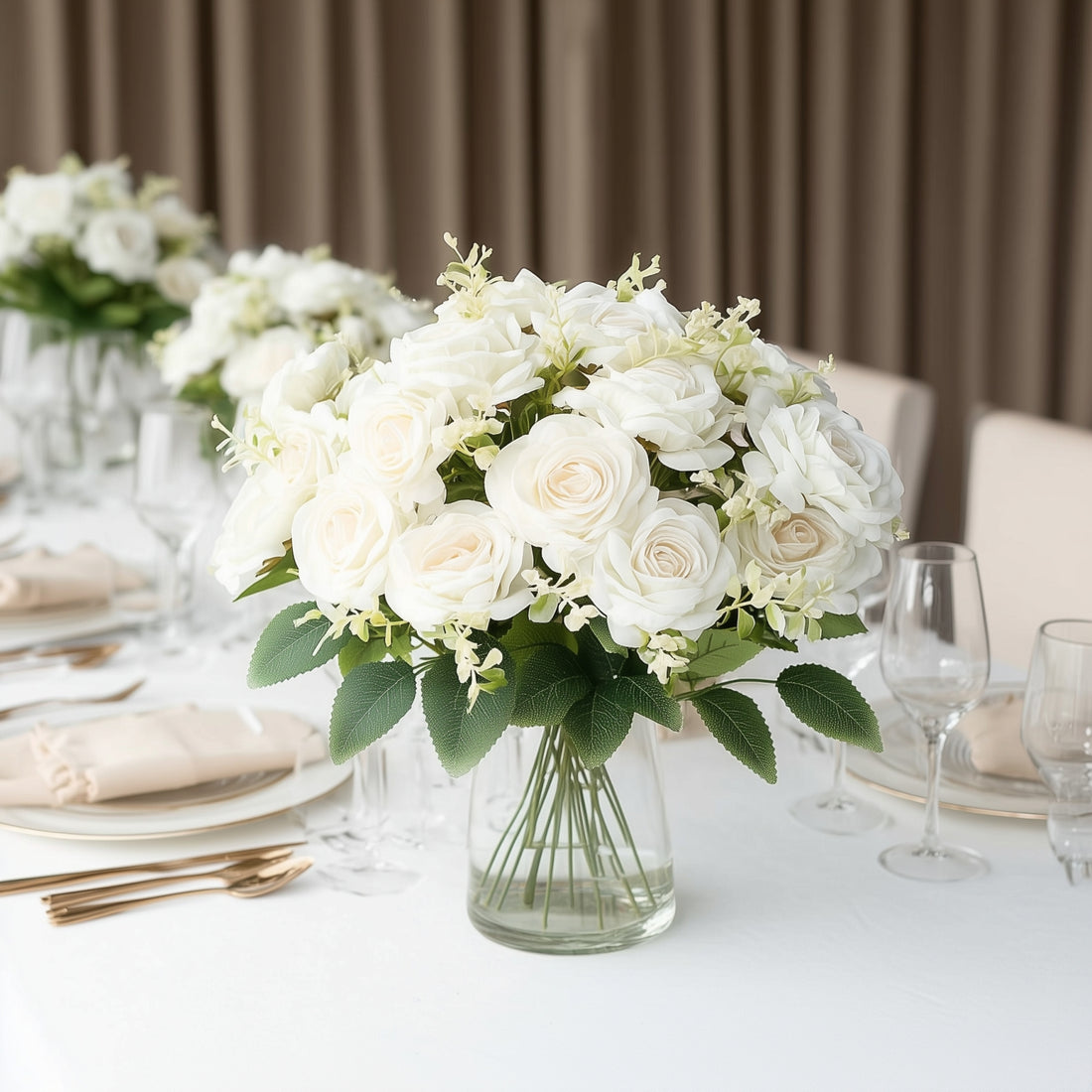 Elegant white floral arrangement in a glass vase on a dining table.