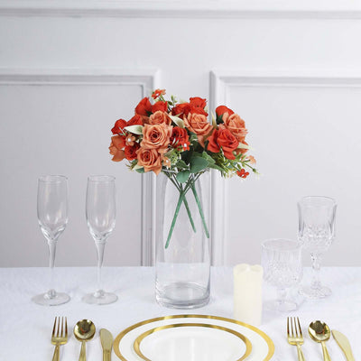 Floral centerpiece arrangement with roses in a glass vase on a dining table.