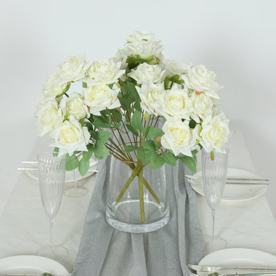 Artificial white rose bouquet in a clear vase on an elegant table setting.