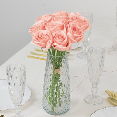 Pink roses in a crystal vase on a dining table setting.