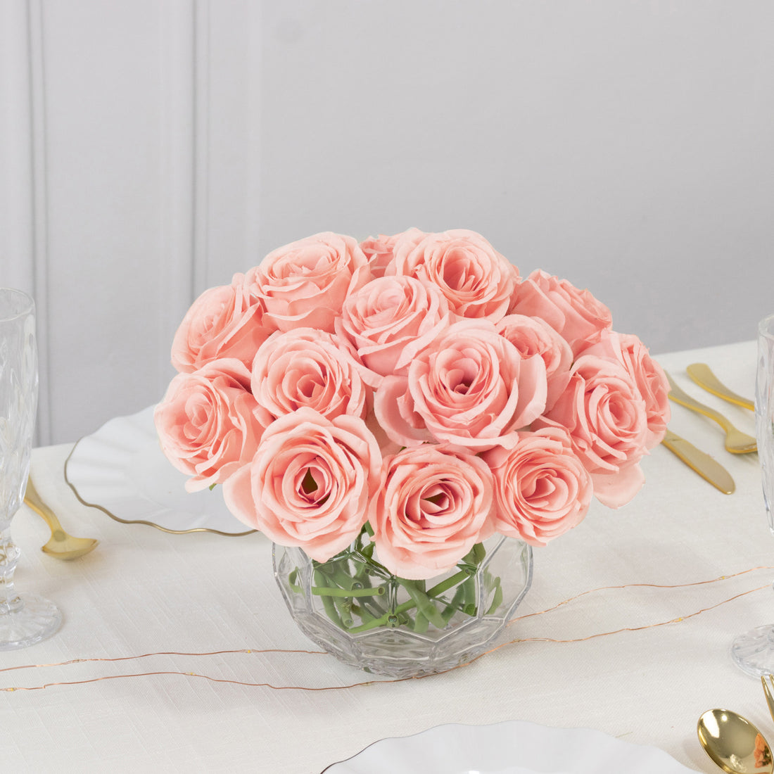 Bouquet of pink roses in a crystal vase on a dining table.