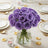 Purple roses in a glass vase, set on an elegant dining table.