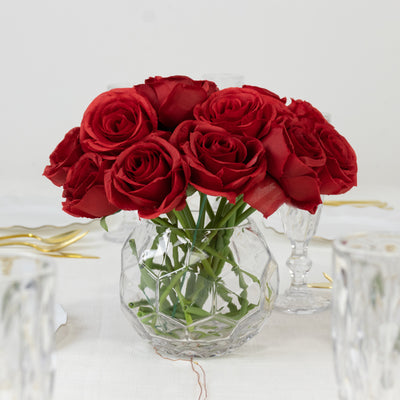 Bouquet of red roses in a clear glass vase on a table.
