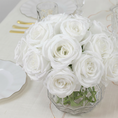 Elegant white rose bouquet in a crystal vase on a table setting.