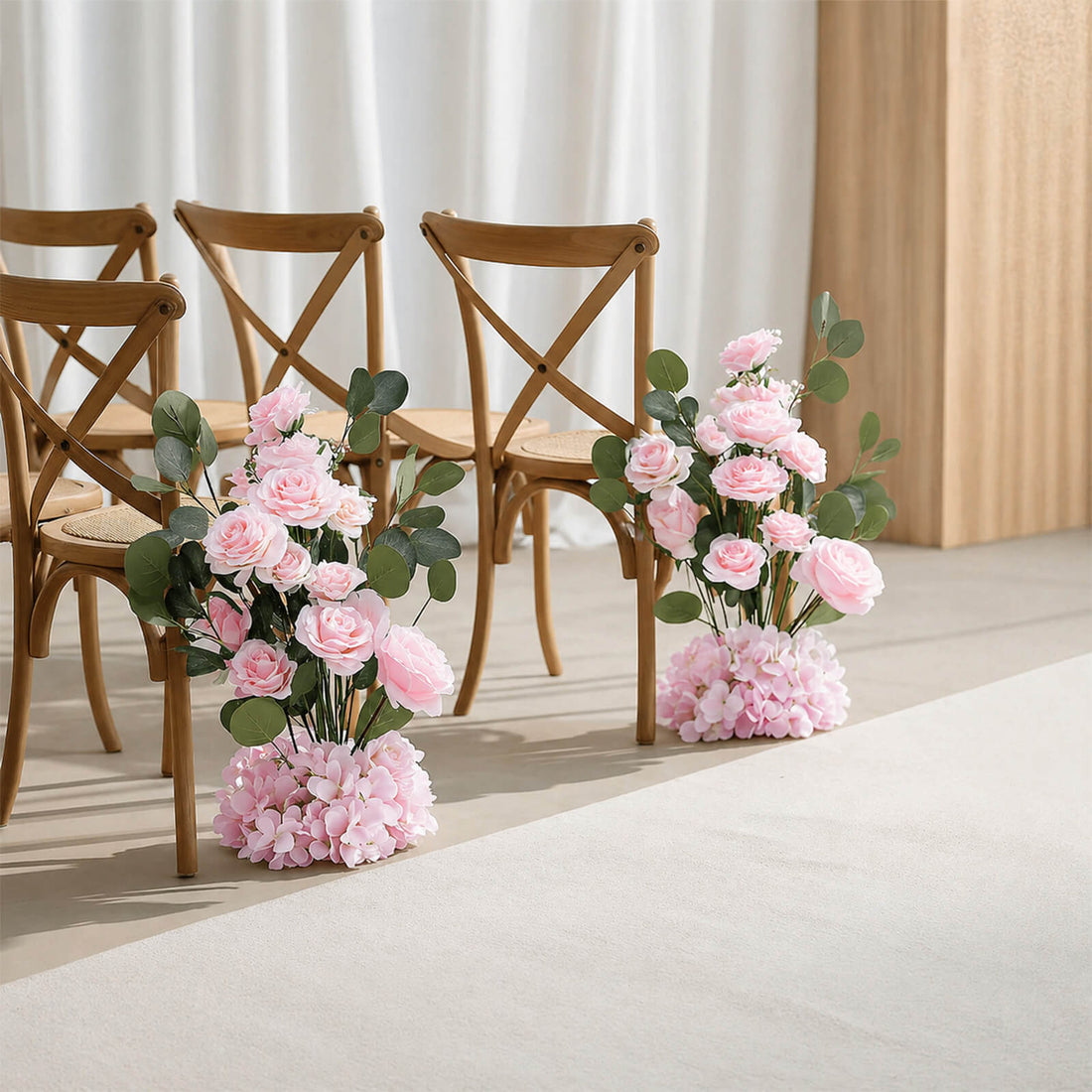 Pink floral wedding chair decorations with wooden chairs in a bright ceremony setting