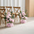 Pink floral wedding chair decorations with wooden chairs in a bright ceremony setting