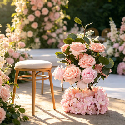 Pastel wedding floral arrangement with wooden stool in sunlit garden setting