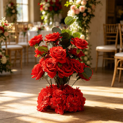 Red rose floral arrangement beside a  in a sunlit wedding venue