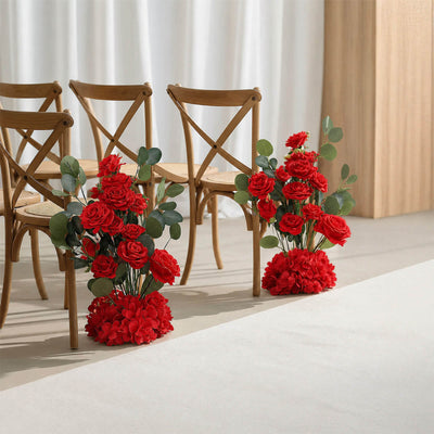 Red rose floral aisle decorations beside wooden chairs in a wedding venue