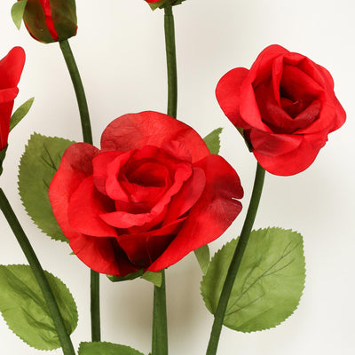 Red paper roses with green leaves on a white background