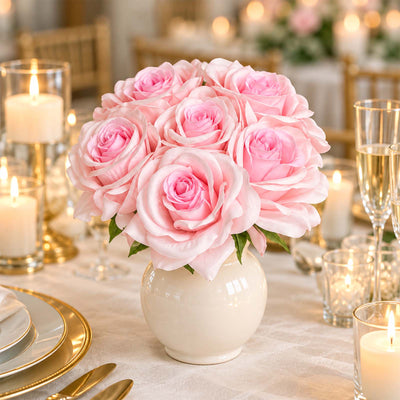 Pink rose centerpiece in white vase on elegant candlelit table setting