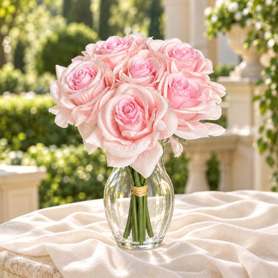 Pink rose bouquet in glass vase on draped table, garden backdrop