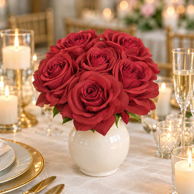 Red rose centerpiece in white vase with candles and gold table setting