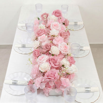 Pink floral table centerpiece with white plates, napkins, and glassware