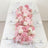 Pink floral table centerpiece with white plates, napkins, and glassware