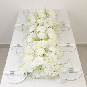 White floral centerpiece on a dining table with elegant glassware and plates.