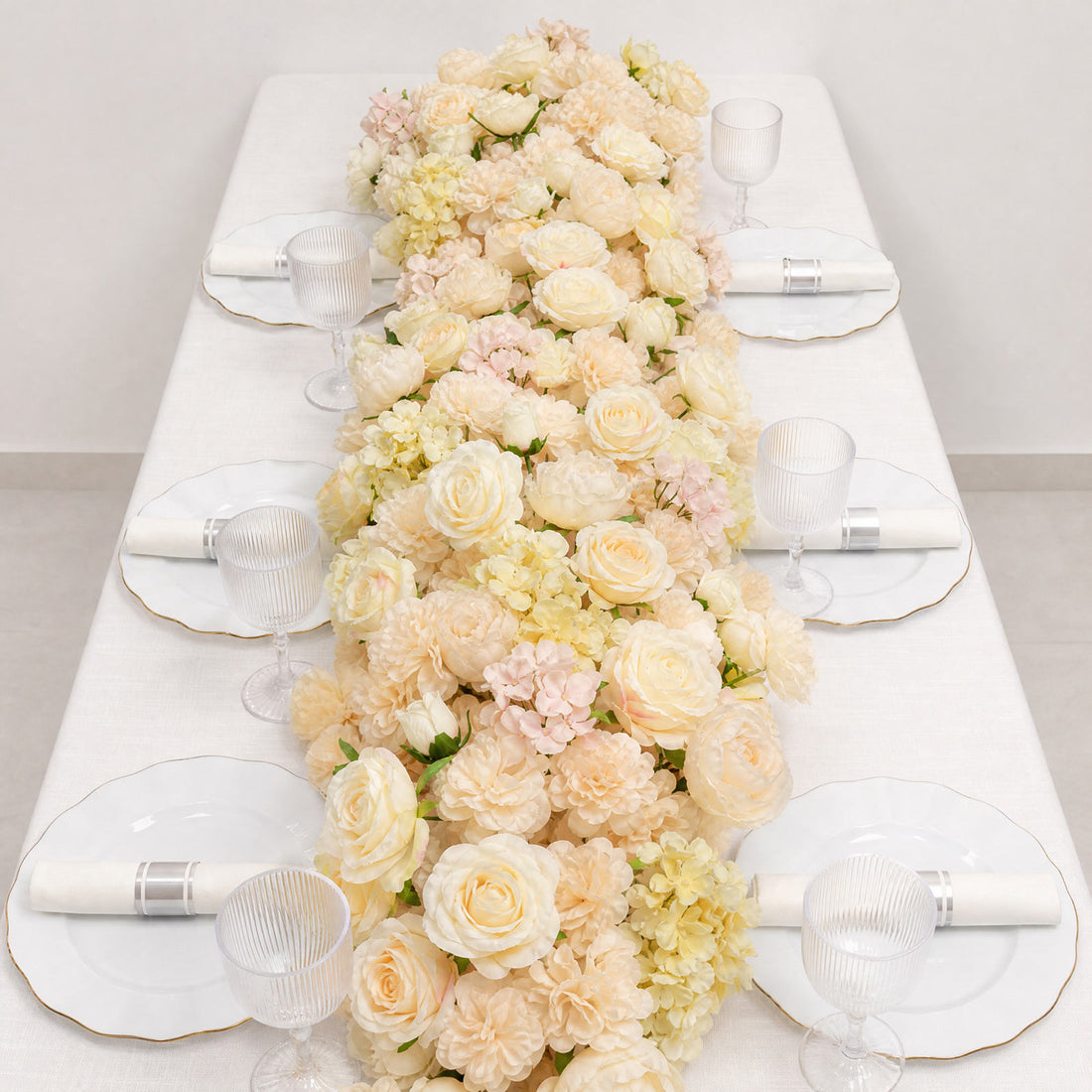 Elegant floral table centerpiece with white plates and glass goblets