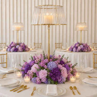 Elegant wedding table centerpiece with purple flowers, gold accents, and candles