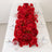 Red floral table runner with white plates and clear glasses on a dining table.
