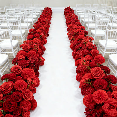 Red floral aisle decoration for wedding ceremony with white chairs.