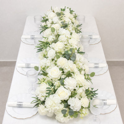Elegant white floral table centerpiece with roses and greenery at a wedding reception
