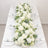 Elegant white floral table centerpiece with roses and greenery at a wedding reception