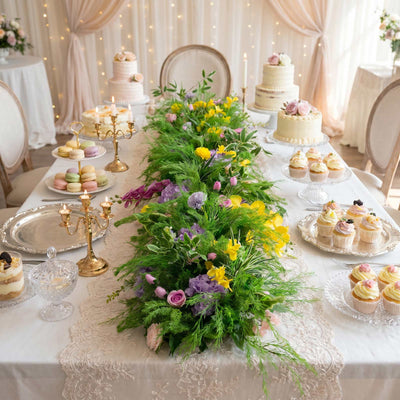 Elegant dessert table with cakes, cupcakes, macarons, and floral centerpiece