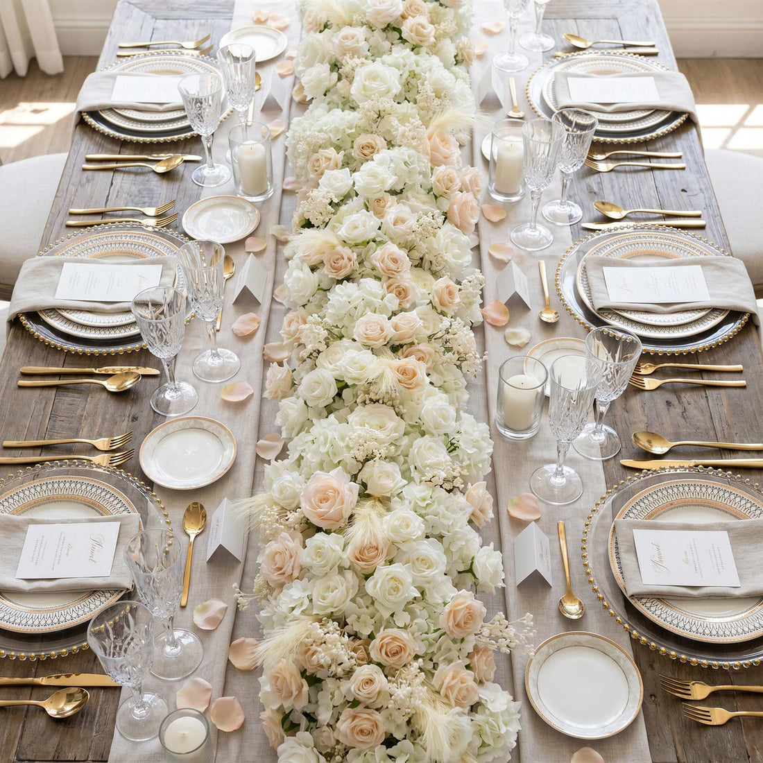 Elegant wedding table centerpiece with white roses, gold accents, and crystal glassware