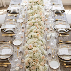 Elegant wedding table centerpiece with white roses, gold accents, and crystal glassware