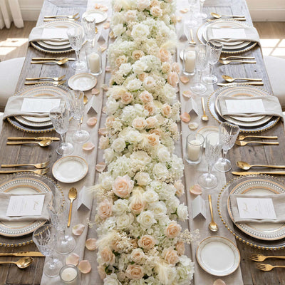 Elegant wedding table centerpiece with white roses, gold accents, and crystal glassware