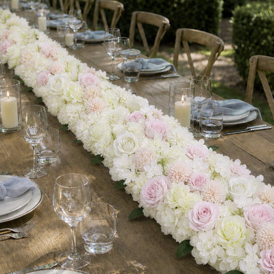 Elegant wedding table with pastel floral garland and candles outdoors