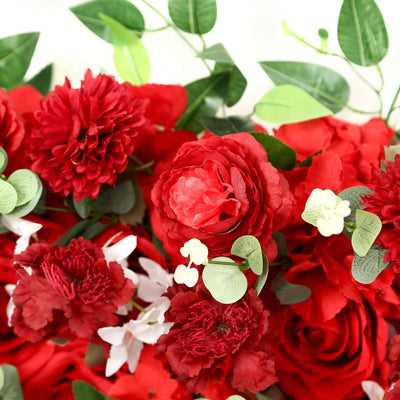 Red artificial flowers with green leaves floral arrangement close-up