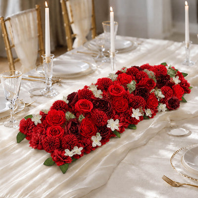 Elegant red floral centerpiece on a candlelit wedding table set with gold accents