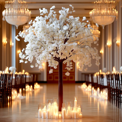 Elegant white floral tree centerpiece with candles in a grand venue.