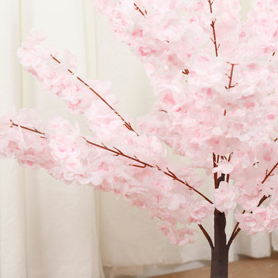 Pink artificial cherry blossom tree in a studio setting.