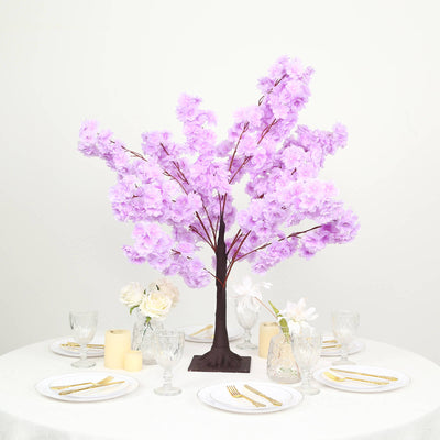 Pink cherry blossom centerpiece on elegant table setting with gold flatware