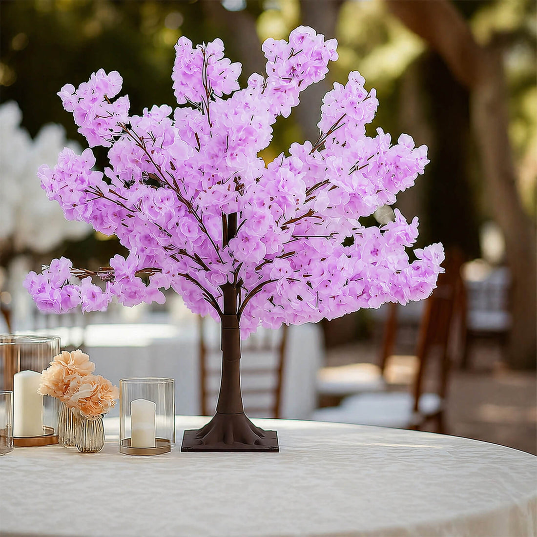 Pink artificial cherry blossom tree centerpiece on a table with candles
