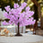 Pink artificial cherry blossom tree centerpiece on a table with candles