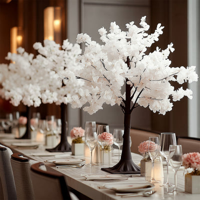 Decorative white flower trees on an elegant dining table setting.