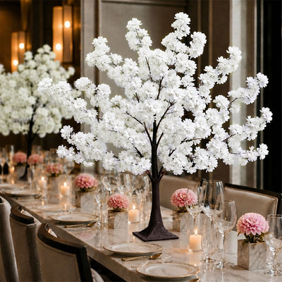 Elegant dining table with white cherry blossom centerpieces and candlelit decor