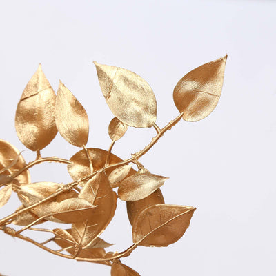 Gold metallic leaves on decorative branch against white background