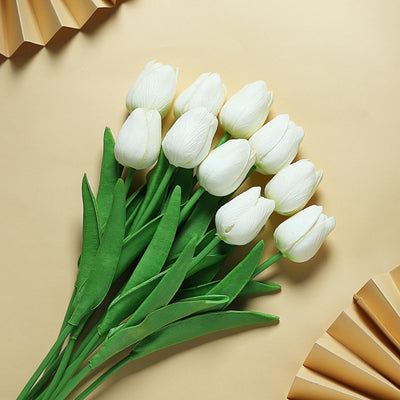 White tulip bouquet with green leaves on a beige background.