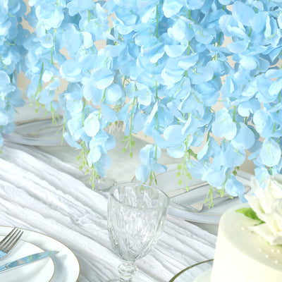 Light blue artificial flowers cascading over a white table setting.