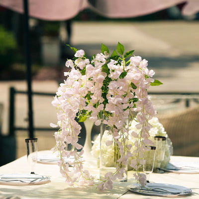 Elegant pink floral arrangement in a glass vase on a dining table setting.