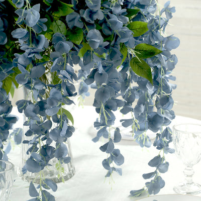 Blue floral arrangement with cascading petals in a glass vase.