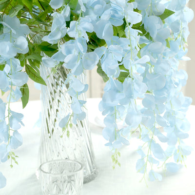 Light blue artificial flowers in a decorative glass vase.